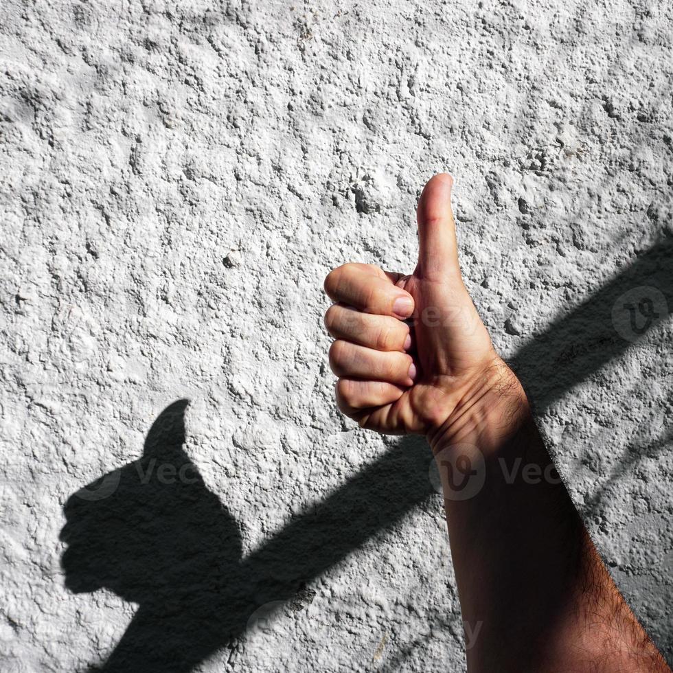 mano en el blanco pared jugando con el oscuridad foto