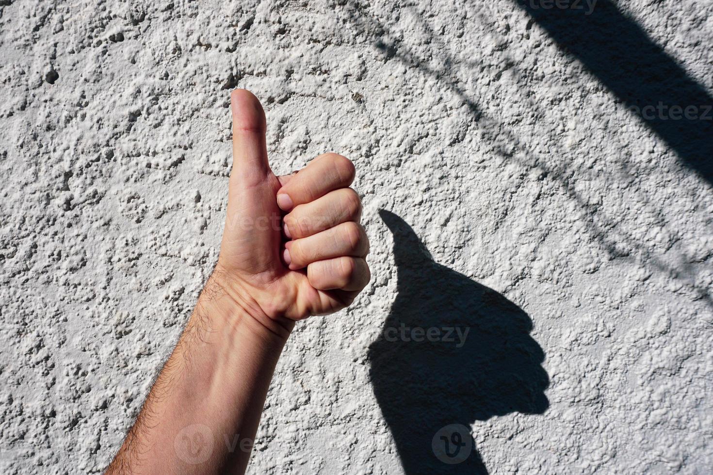 mano en el blanco pared jugando con el oscuridad foto