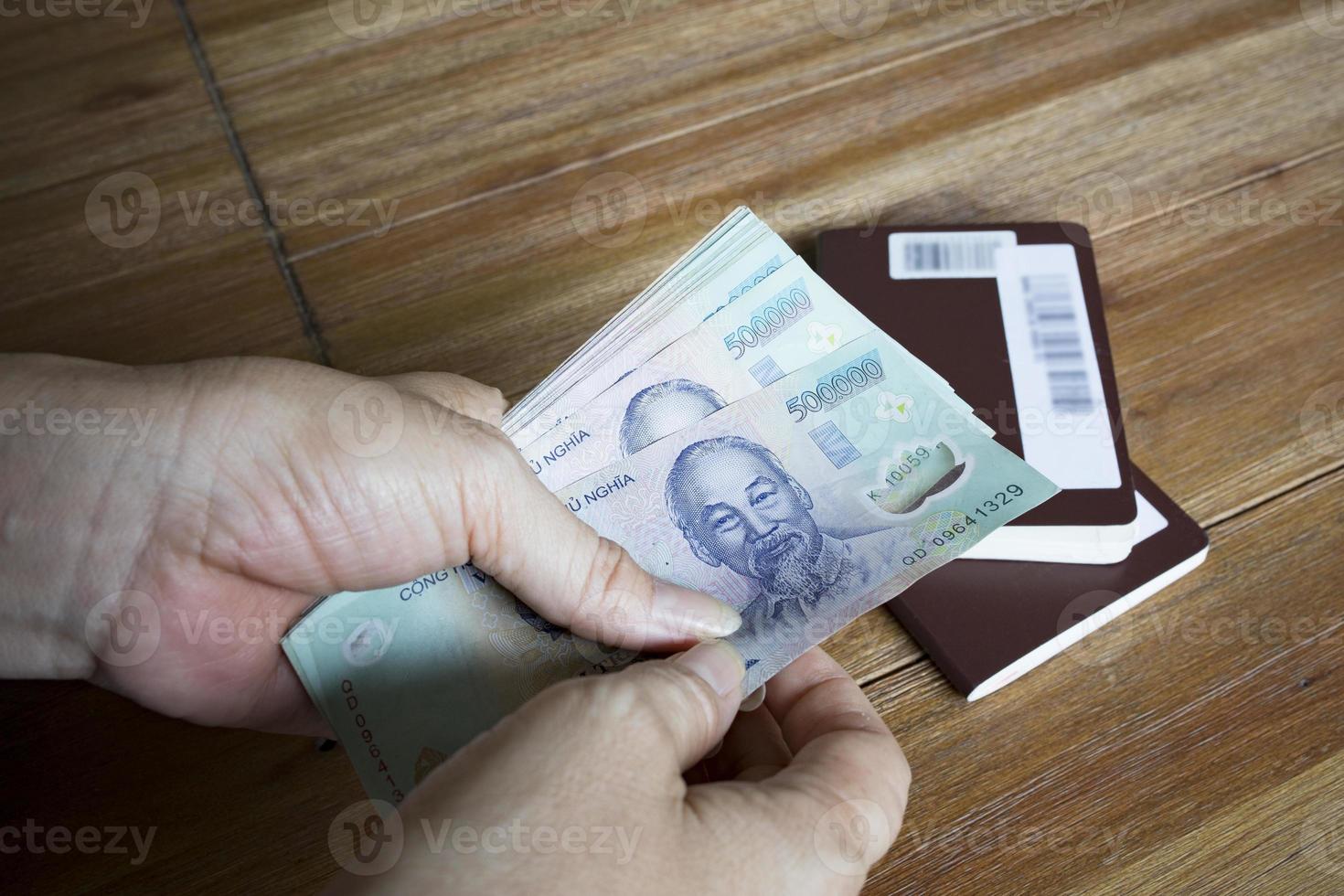 woman hand hold for counting vietnam dong banknote  with passport book on  wood table photo