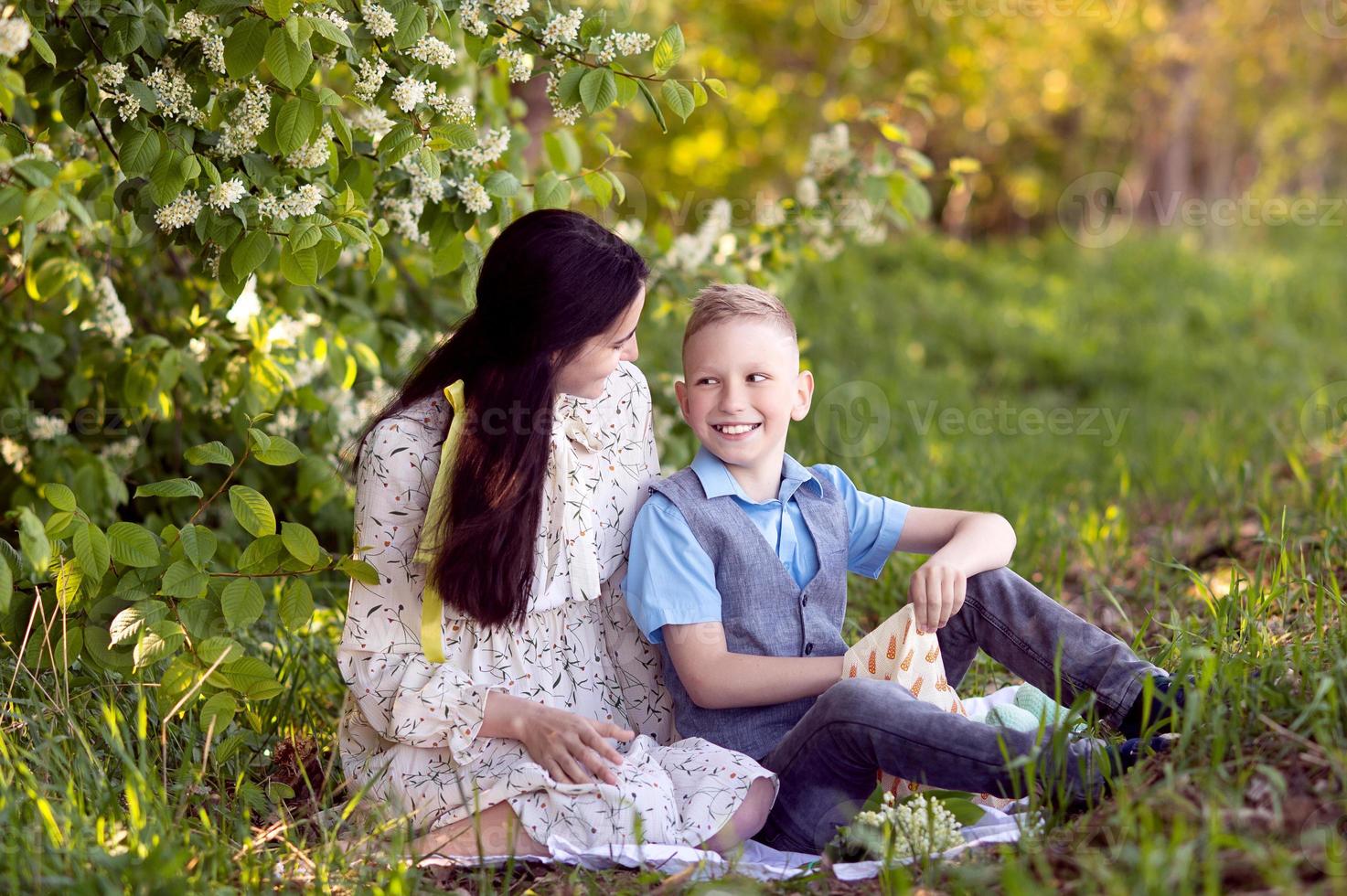 Mom hugs her little son , who is holding a bouquet of lilies of the valley in his hands photo