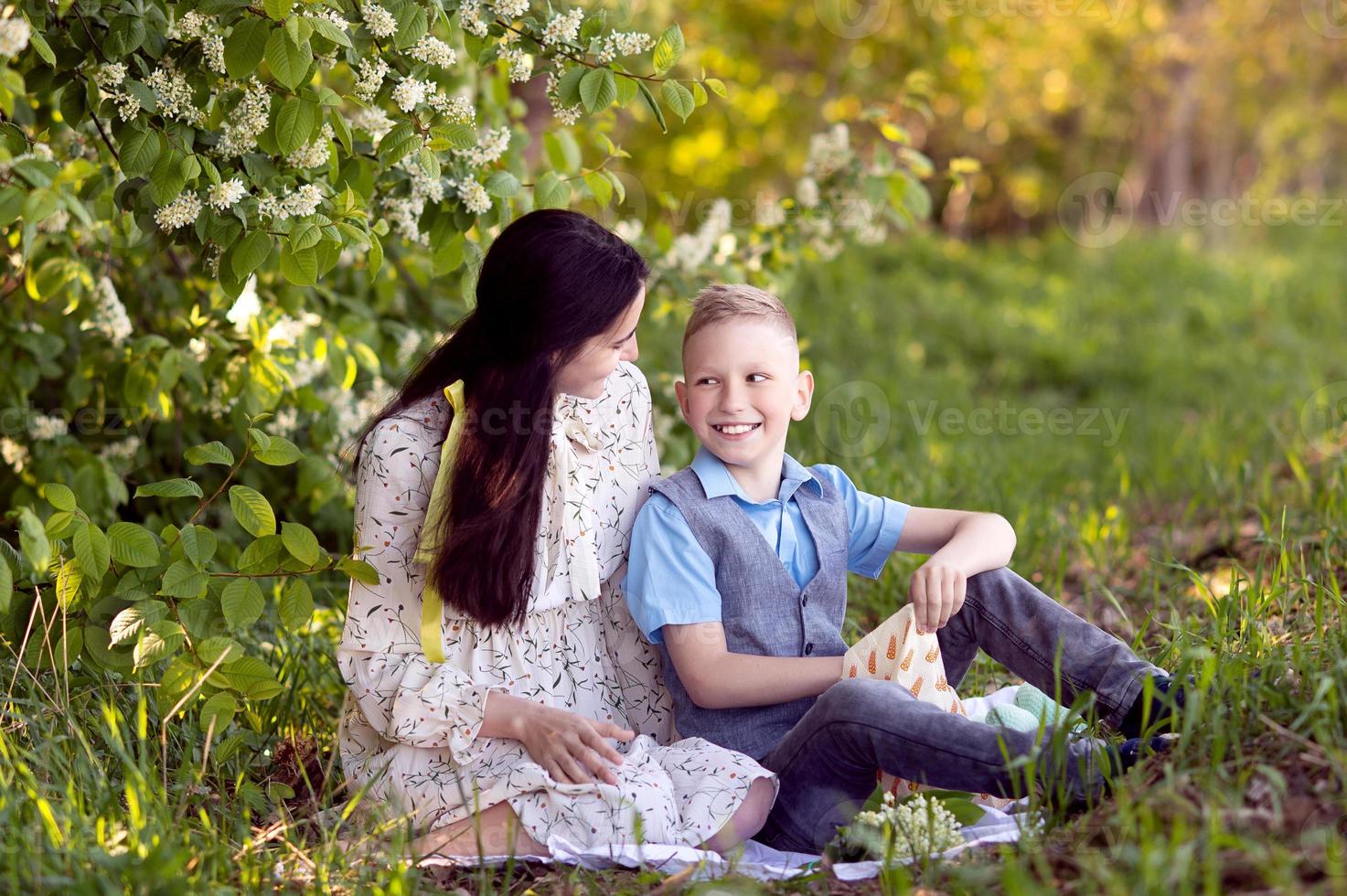 mamá abrazos su pequeño hijo , quien es participación un ramo de flores de lirios de el Valle en su manos foto