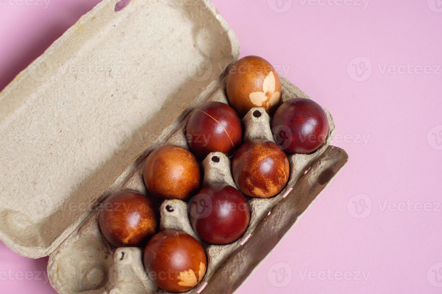 Painted red eggs lie in an eco-friendly tray on a pink background photo