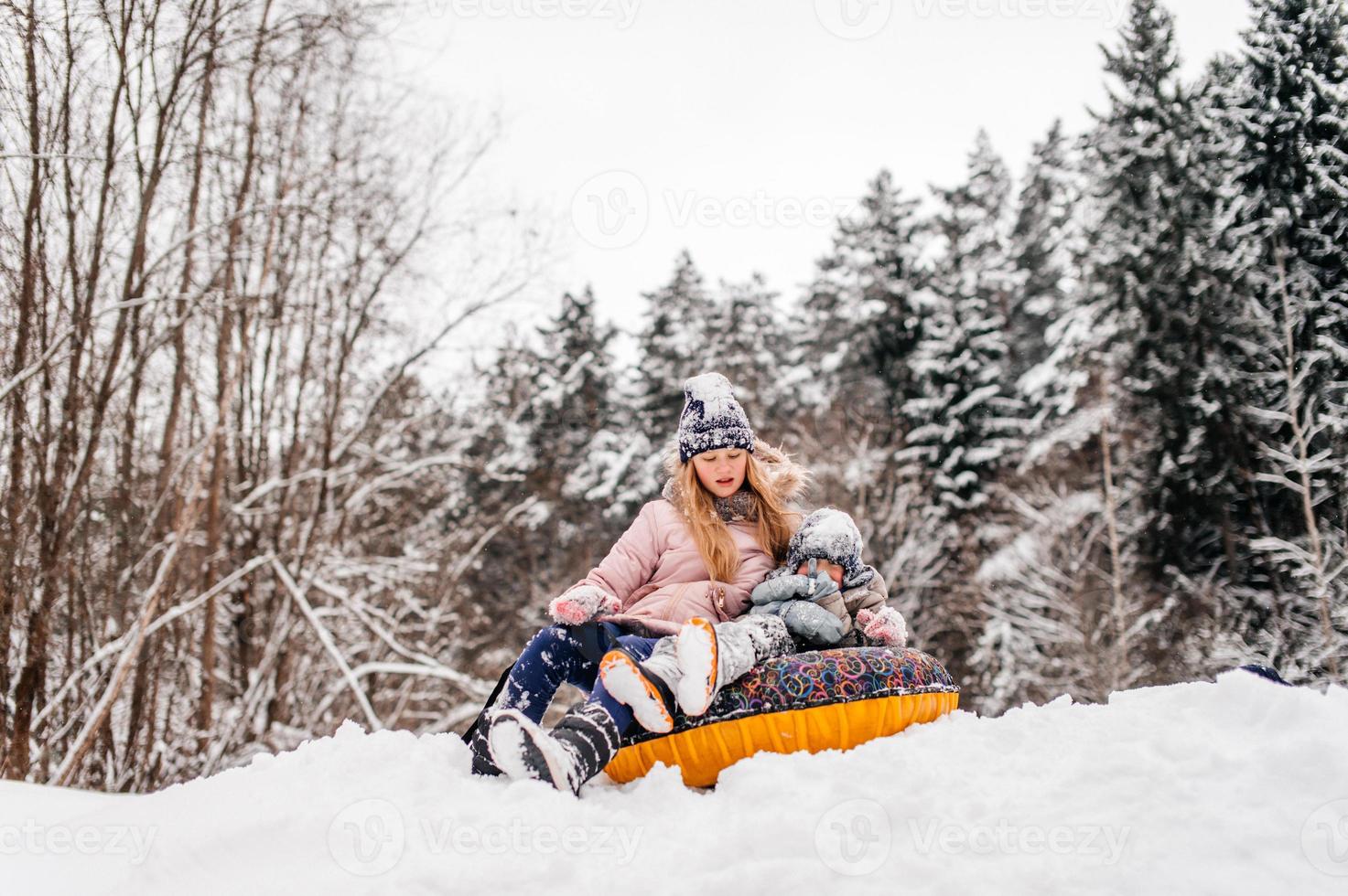 Boys and a girl are sitting in a tubing in the snow photo