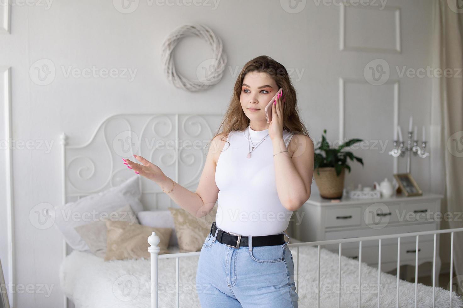 Thoughtful emotional European girl in a white top is talking on the phone. photo