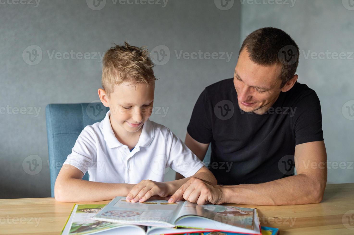 un linda chico es sentado a el mesa con su papá y acecho un libro acerca de mariposas foto