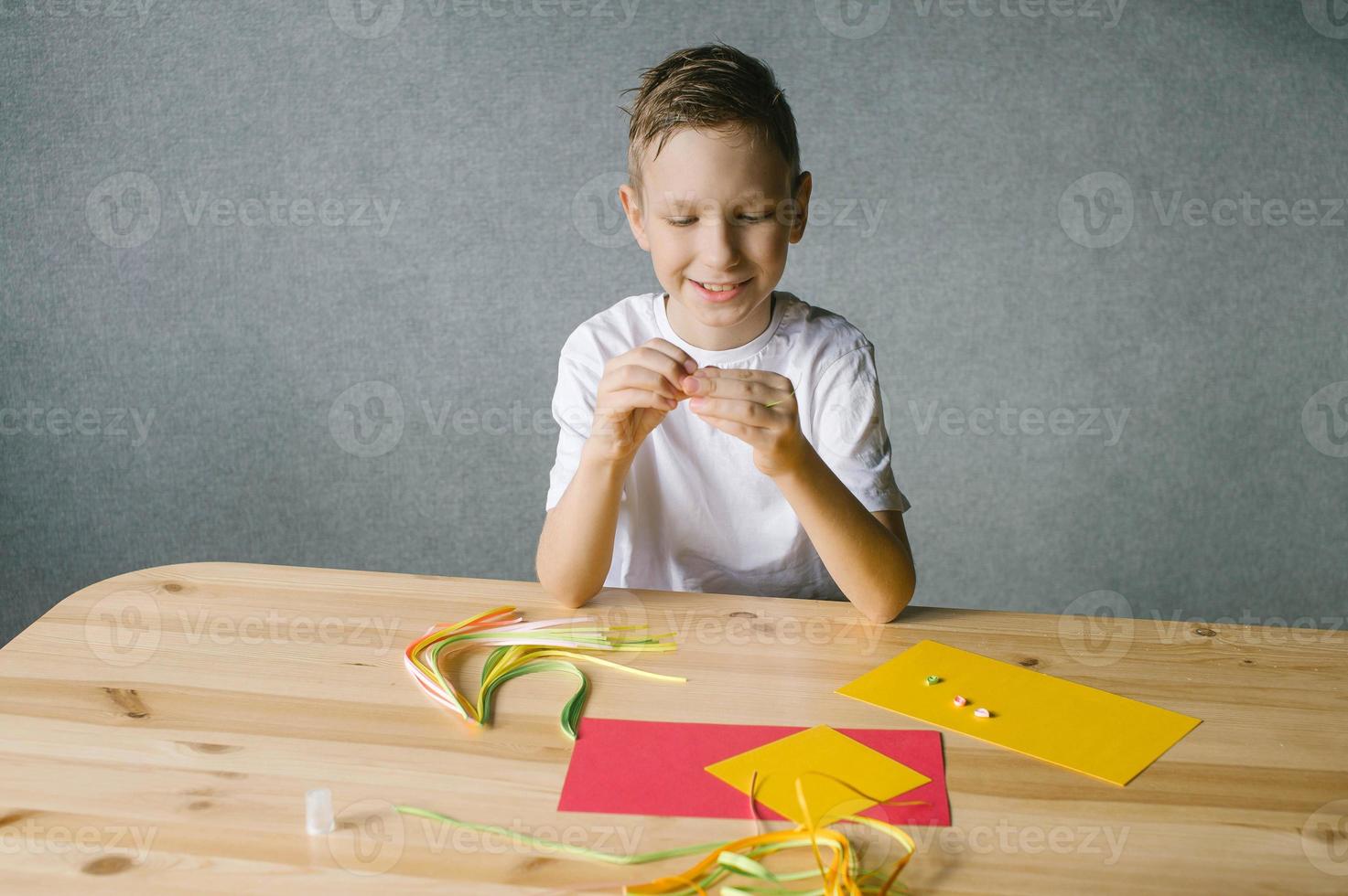 Cute boy makes a card by quilling while sitting at the table photo
