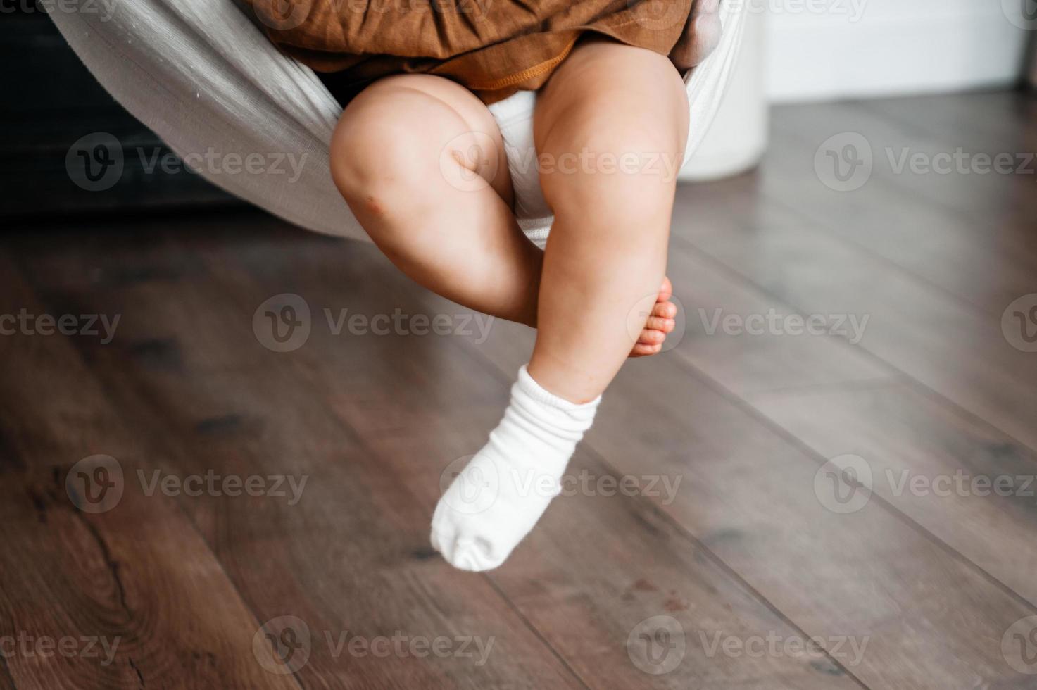 Children's feet in socks hang on the background of the floor photo