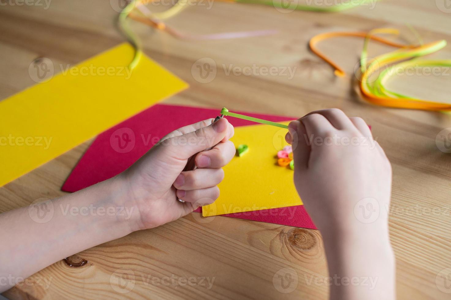 With the hands of a child, make a card out of quilling, twist a strip of narrow paper with an awl photo