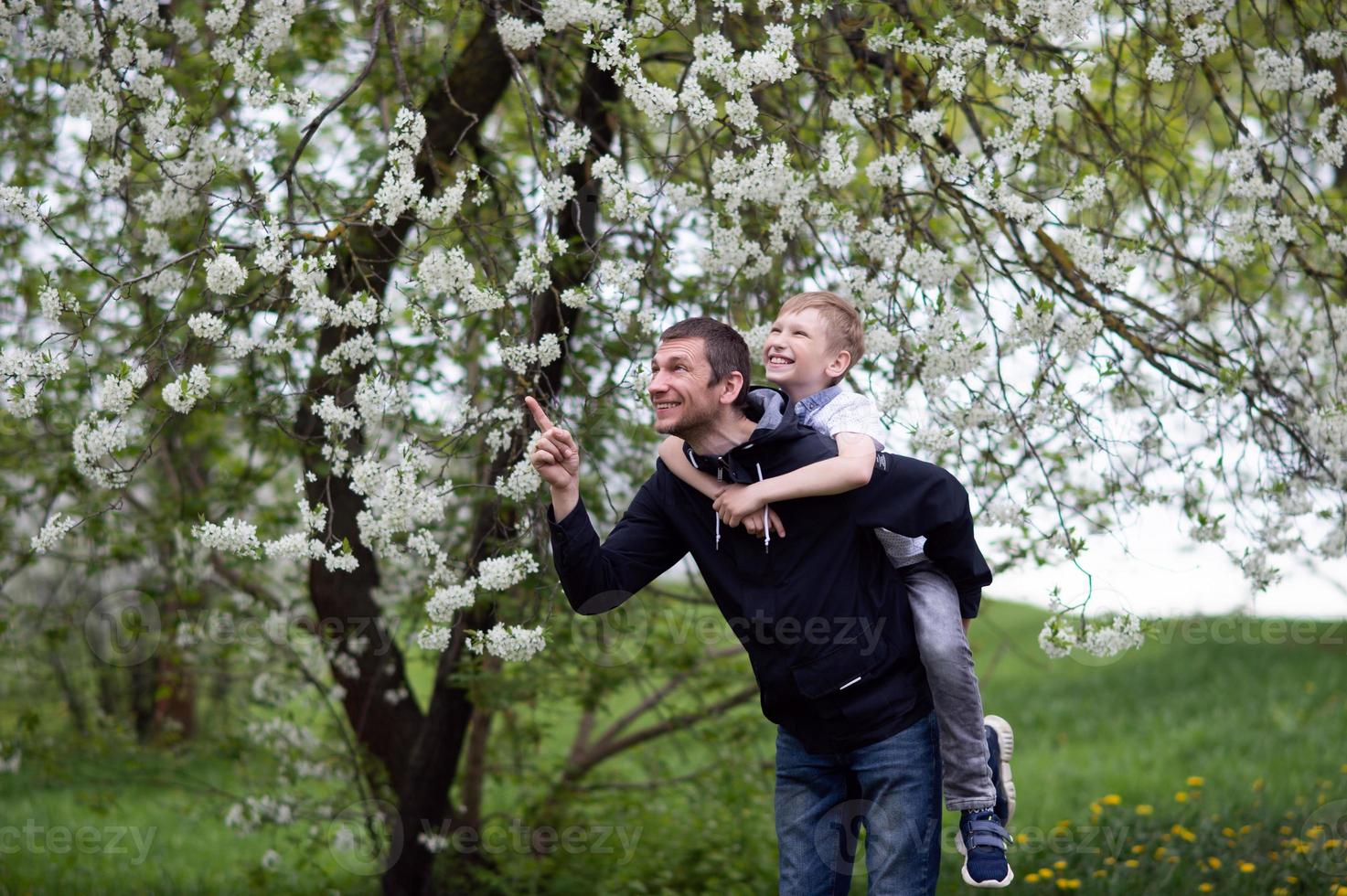 The boy is sitting on Dad's back and they are laughing photo