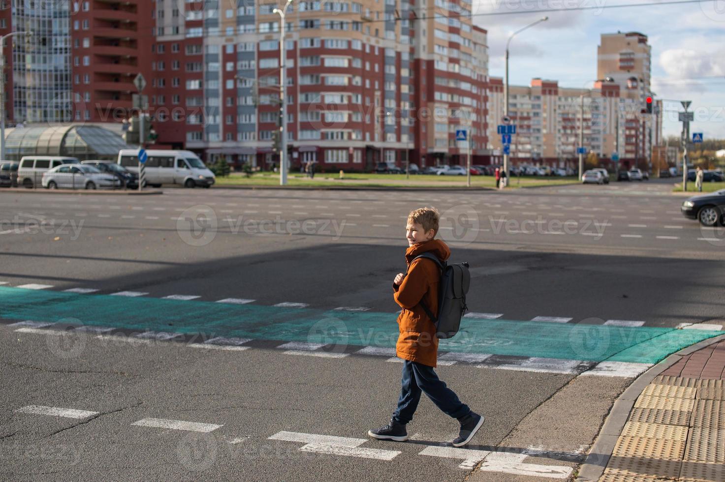 un estudiante cruces el la carretera a un peatonal cruce foto