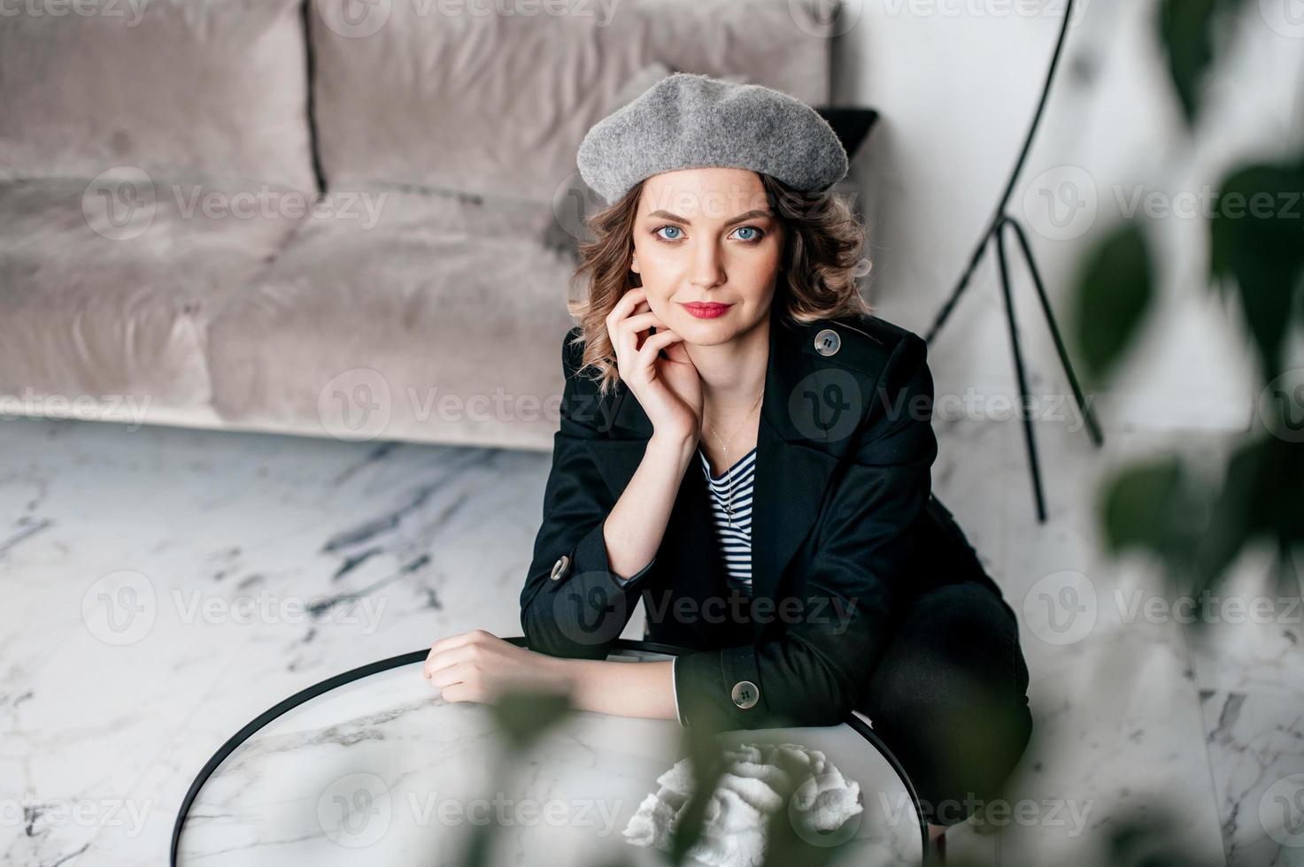 A girl in a beret and with red lipstick looks at the camera photo