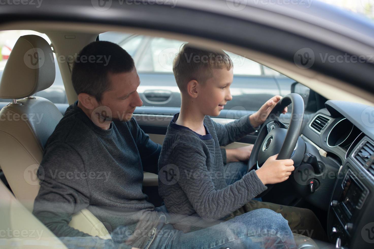 papá muestra su pequeño hijo cómo a conducir un coche foto