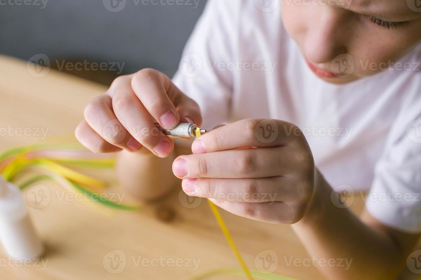 Cute boy makes details for a postcard by quilling method, sitting at a table photo