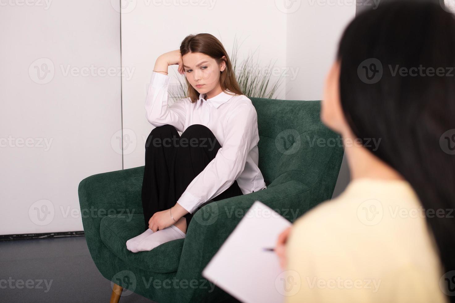 A young girl is sitting in a psychologist's office, sharing her experiences photo