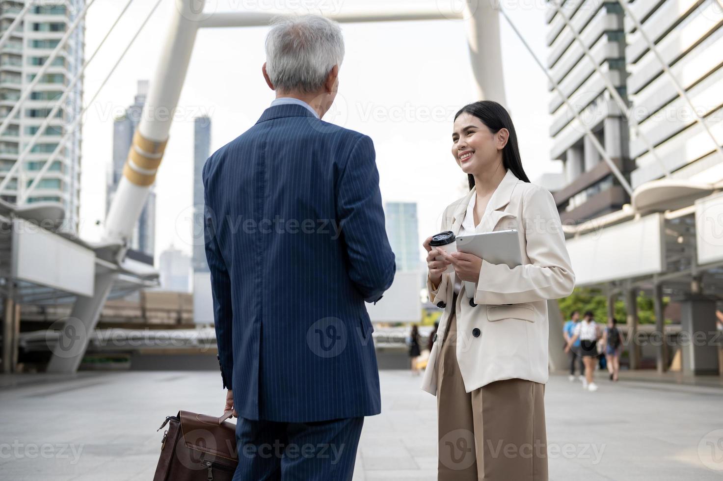 Asian senior mature middle aged businessman and young businesswoman having a discussion and coffee in modern city photo