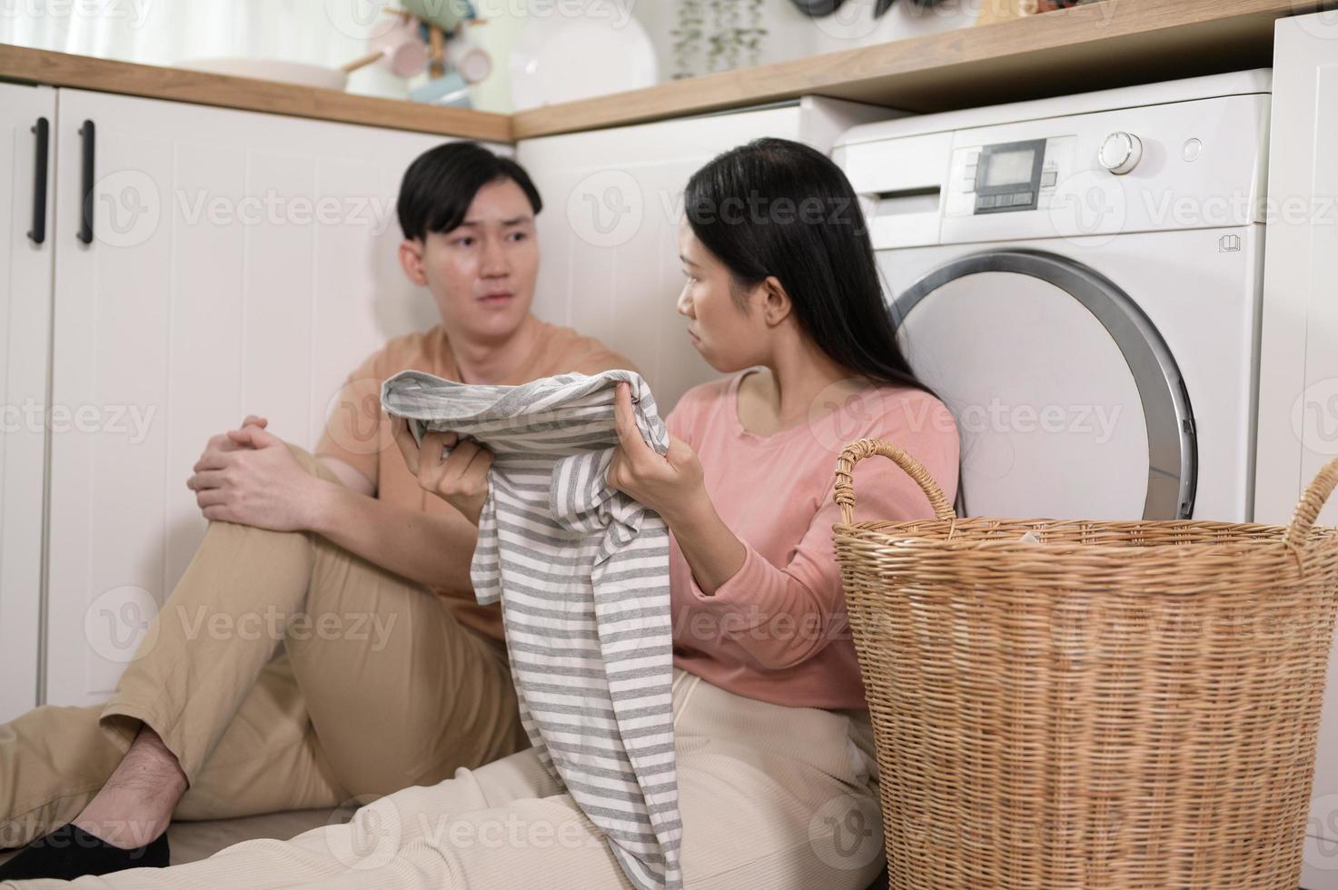 asiático joven Pareja haciendo lavandería juntos sensación intentó , aburrido , discutiendo acerca de el relación problema . foto