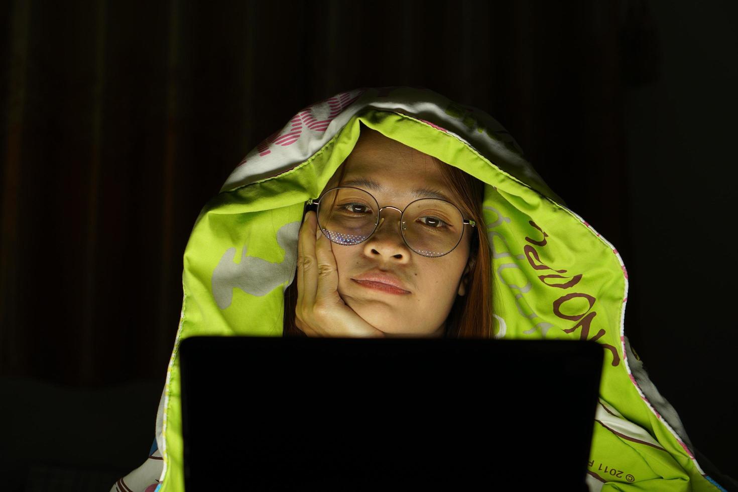 Asian woman wearing glasses To view the computer in low light watch movies online photo