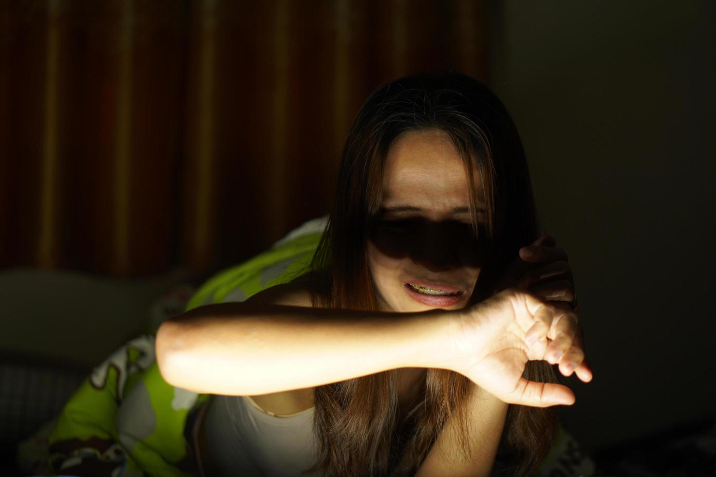 asiático mujer sufrir desde fatiga visual desde mirando a ordenadores en bajo ligero. reloj películas en línea foto