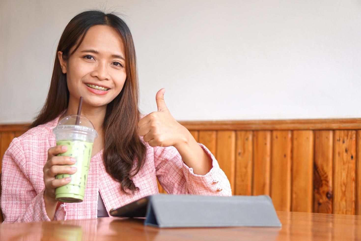 Asian woman braces watch computer Drink green tea to refresh. photo