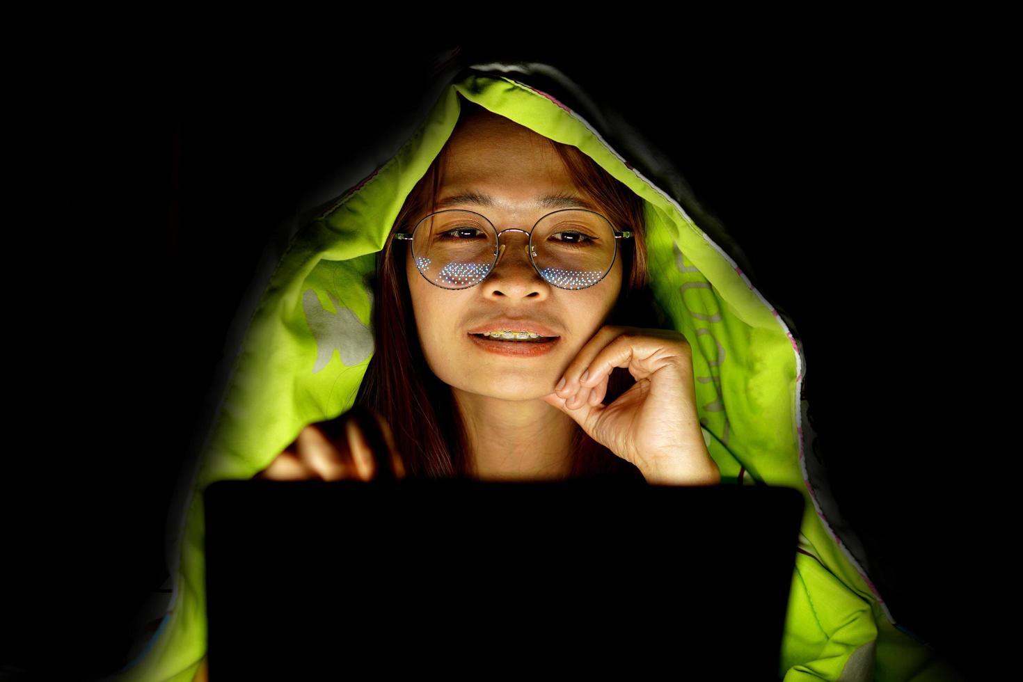 Asian woman wearing glasses To view the computer in low light watch movies online photo