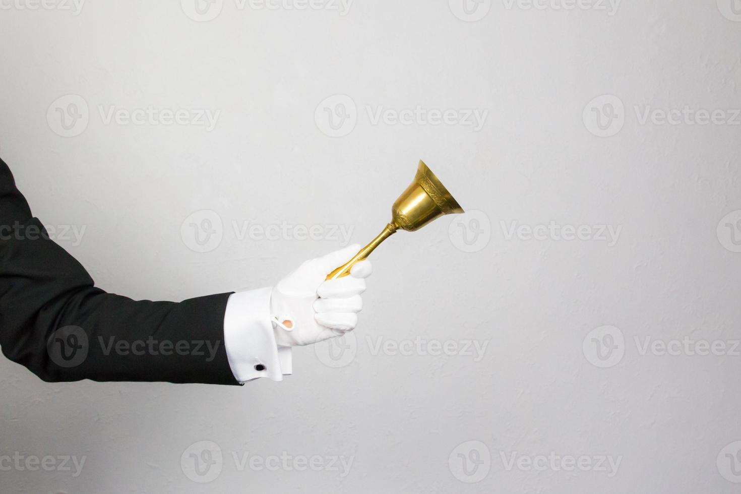 Isolated Close Up of Butler Or Waiter Holding Brass Bell. Concept of Service Industry and Professional Hospitality. photo