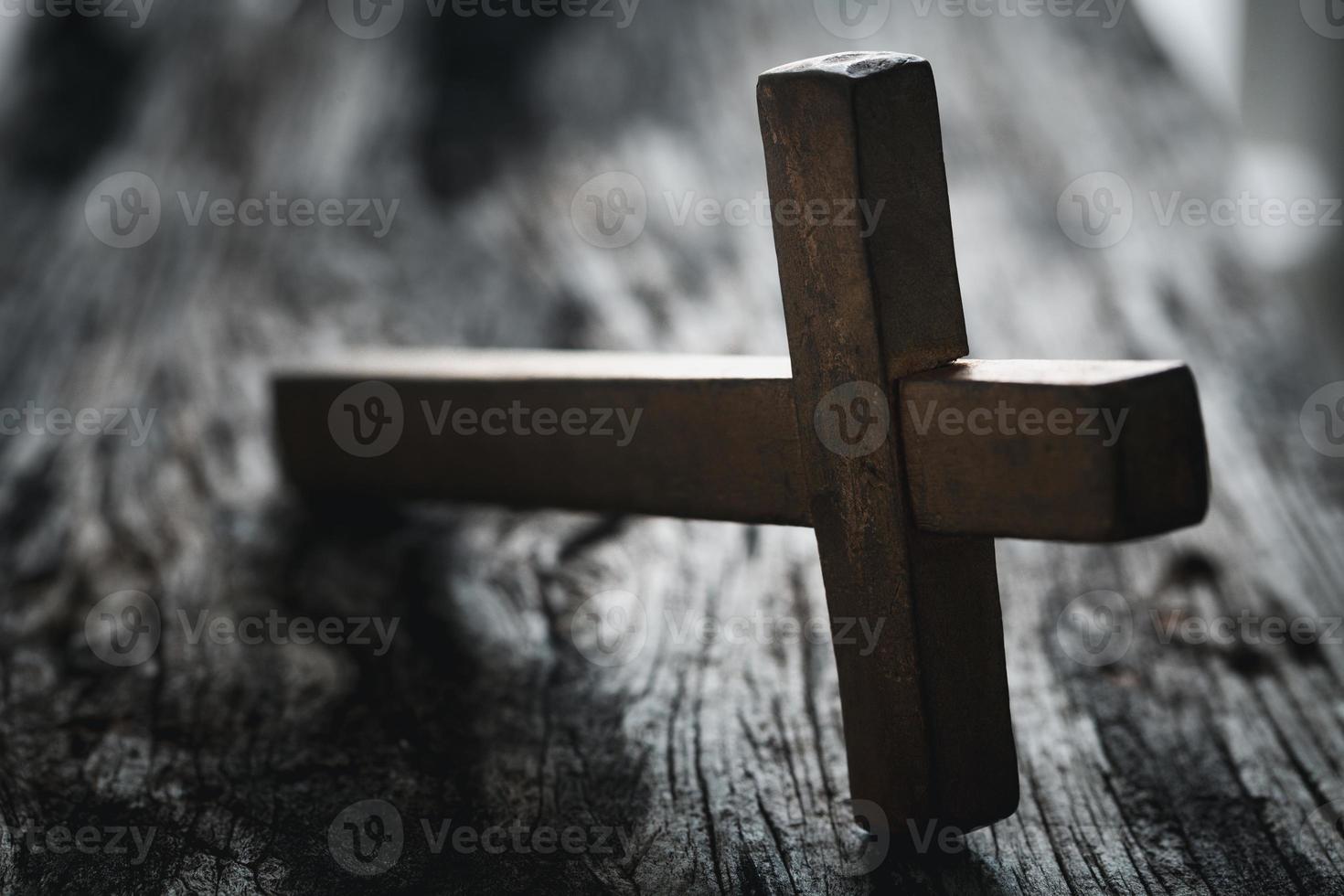 A wooden Christian cross crucifix on a grunge board background. Wooden Christian cross on grey table against blurred lights, space for text. photo