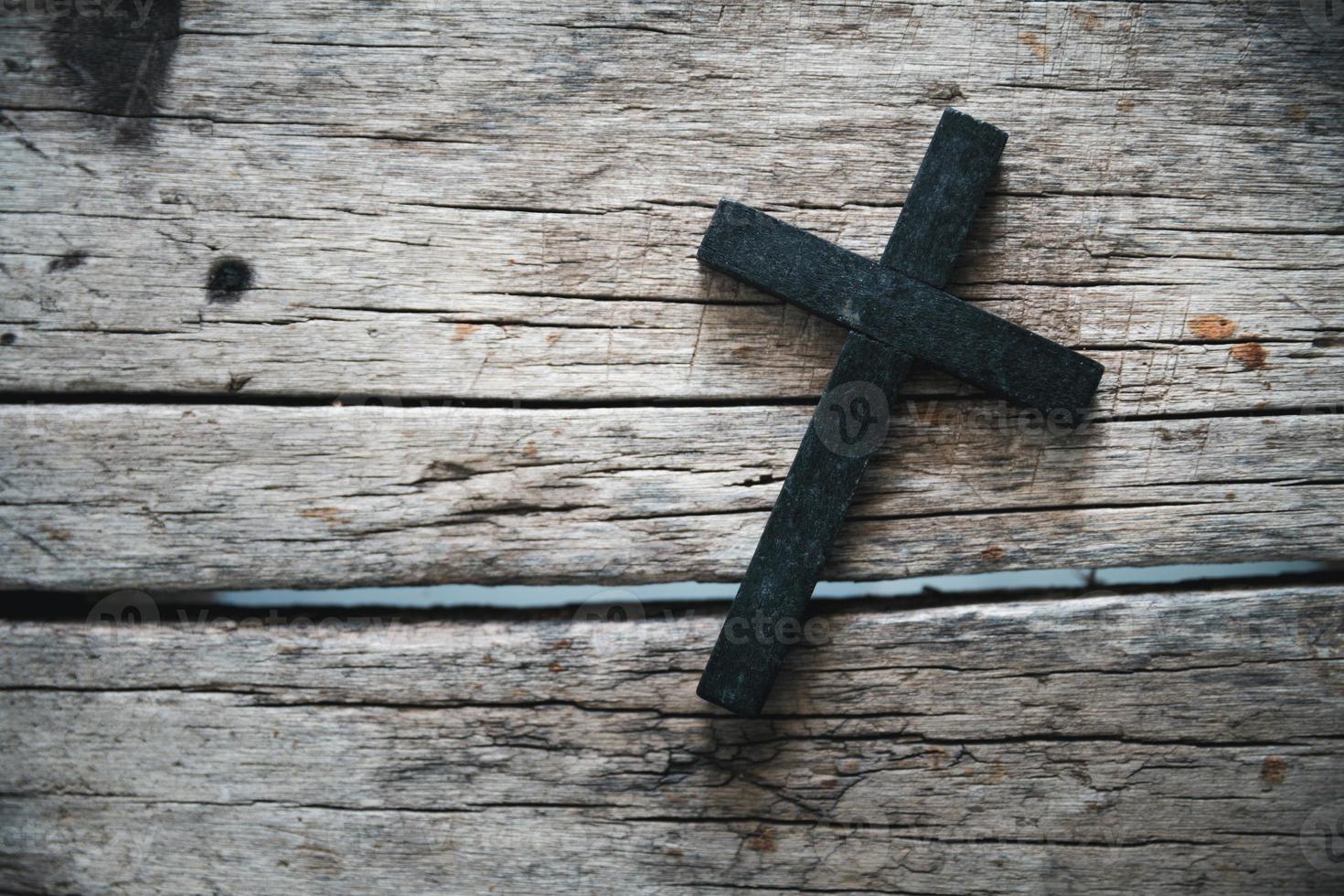 A wooden Christian cross crucifix on a grunge board background. Wooden Christian cross on grey table against blurred lights, space for text. photo