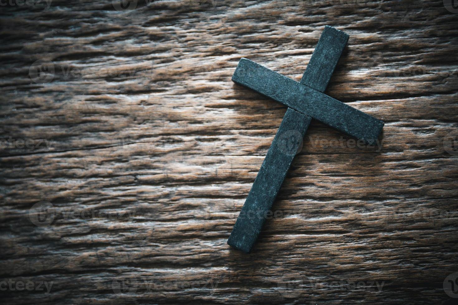 A wooden Christian cross crucifix on a grunge board background. Wooden Christian cross on grey table against blurred lights, space for text. photo