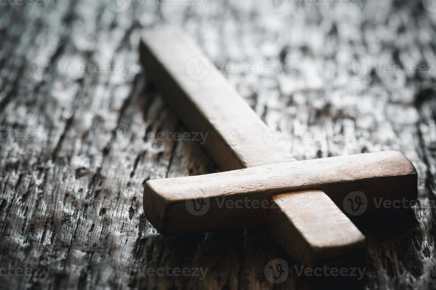 A wooden Christian cross crucifix on a grunge board background. Wooden Christian cross on grey table against blurred lights, space for text. photo