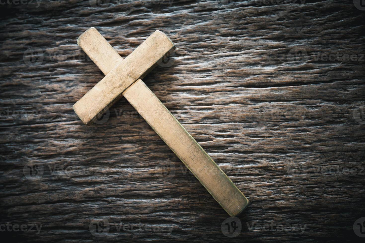A wooden Christian cross crucifix on a grunge board background. Wooden Christian cross on grey table against blurred lights, space for text. photo