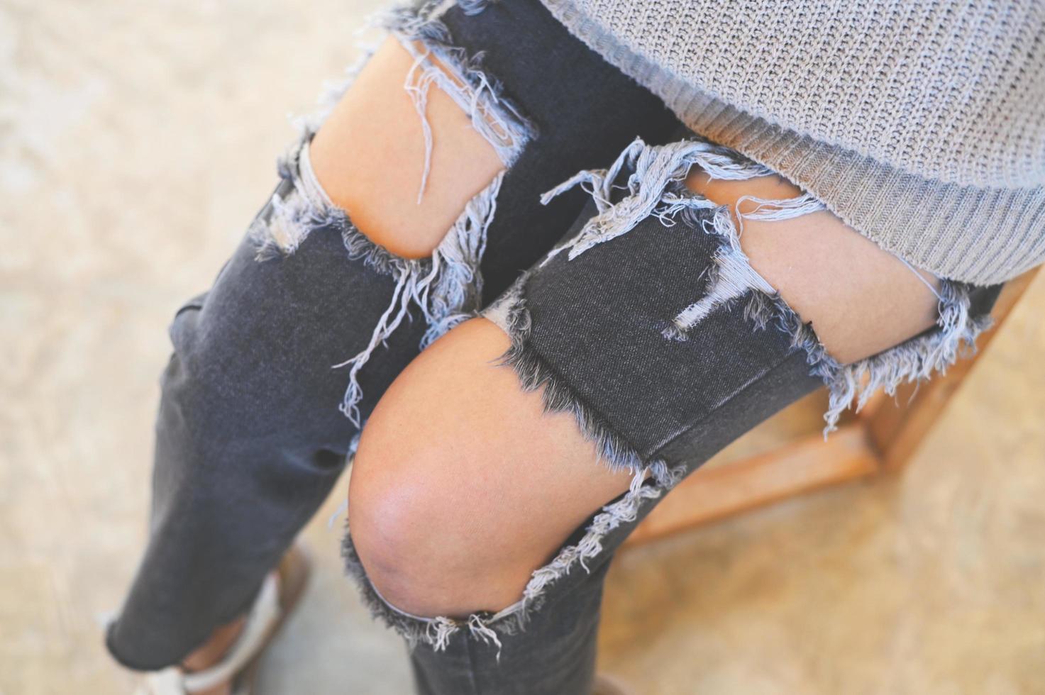 torn pants , torn jeans, close up girl wear jean - women knees in jeans holes in jeans, fashion clothing. Hips and knees in fashionable jeans photo