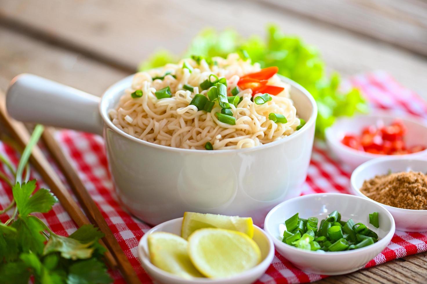 noodles bowl with vegetable spring onion lemon lime lettuce celery and chili on wooden table food , instant noodles cooking tasty eating with bowl - noodle soup photo