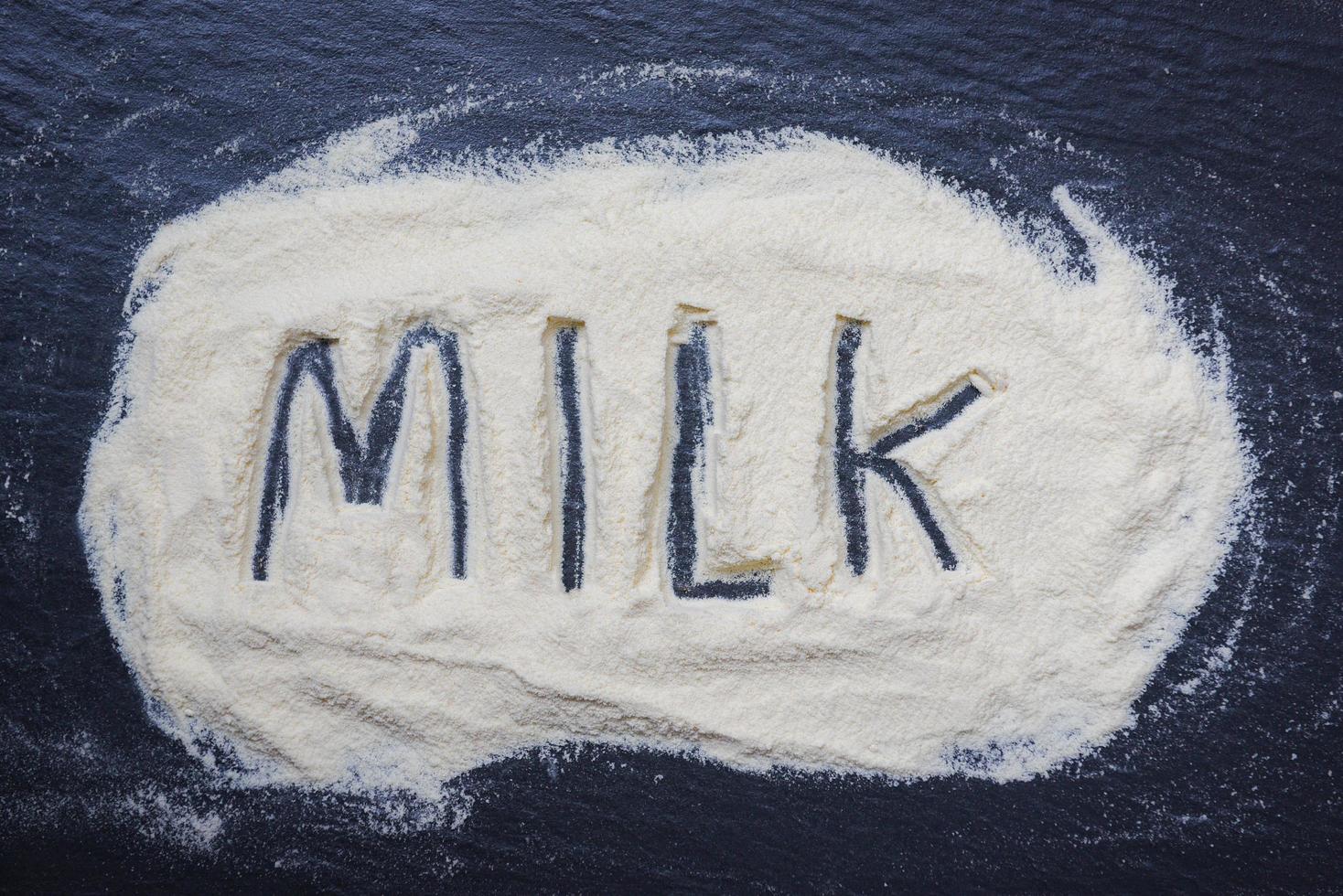 Milk powder on dark background - powdered milk text top view , food healthy body from protein or for baby concept photo