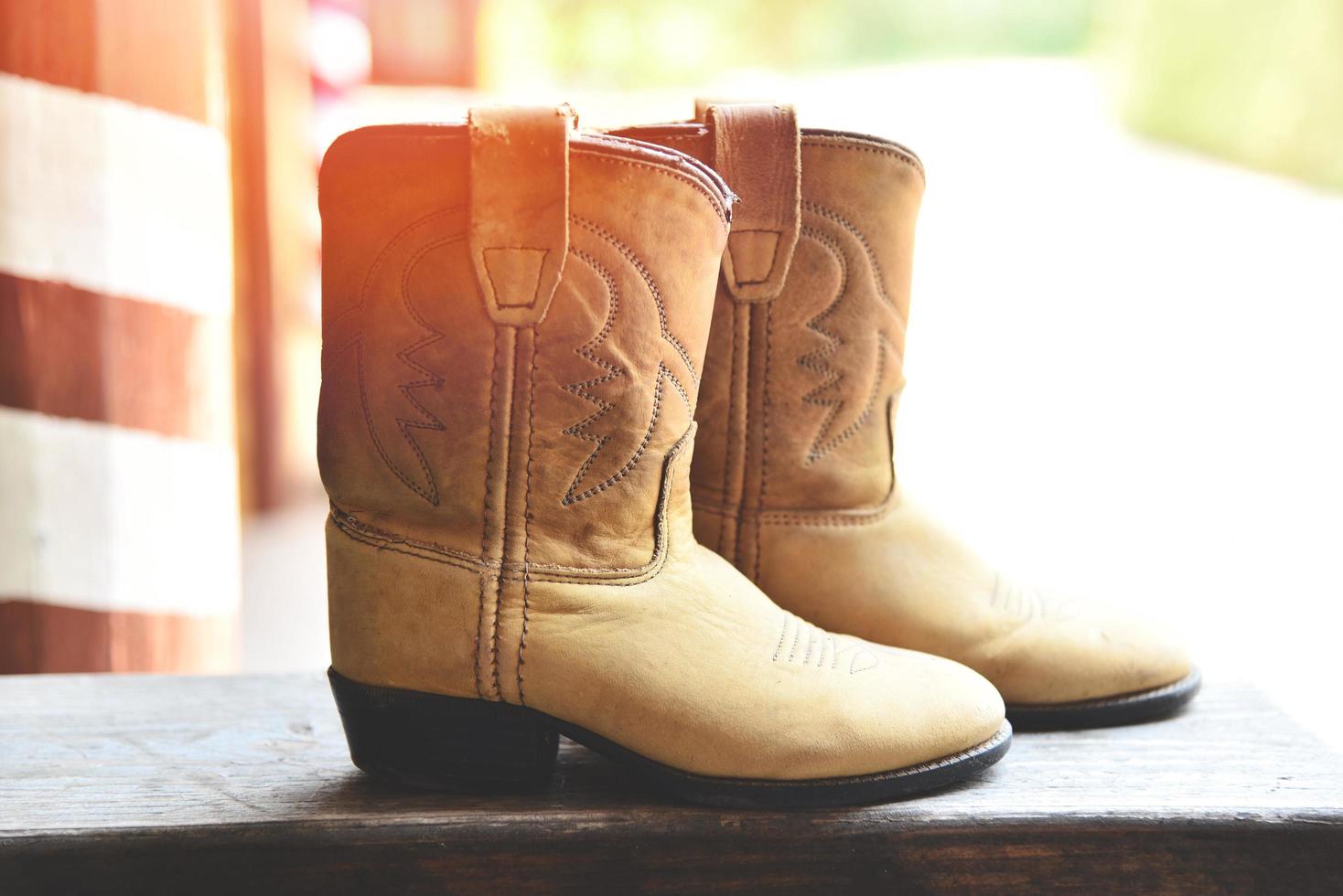 Cowboy Boots - American Wild West retro cowboy rodeo pair of traditional leather roper style western on wooden vintage style in the countryside photo