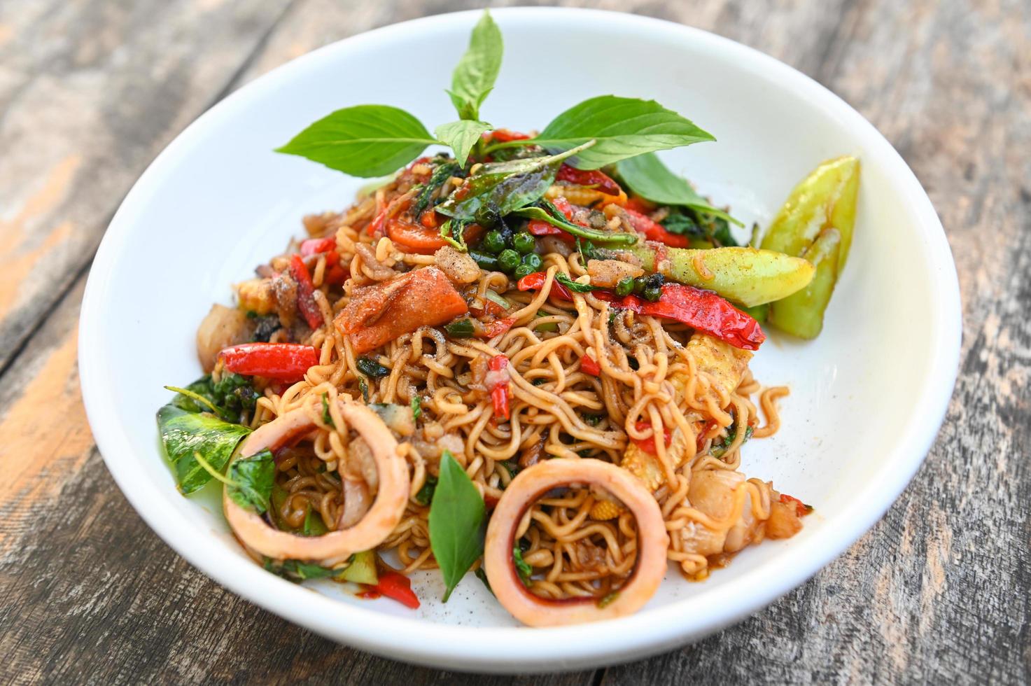 noodles plate with instant noodles stir fried with vegetables herb spicy tasty appetizing asian noodles mix seafood stir fried squid with basil and chilli pepper photo