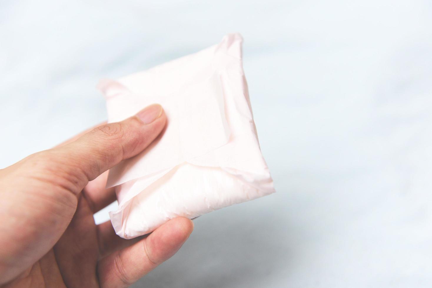 Holding Sanitary napkin or feminine sanitary pad on hand - Female hygiene means women Period Product absorbent sheets photo