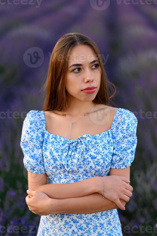 Attractive slender happy girl in a blue dress in a lavender field at sunset. photo