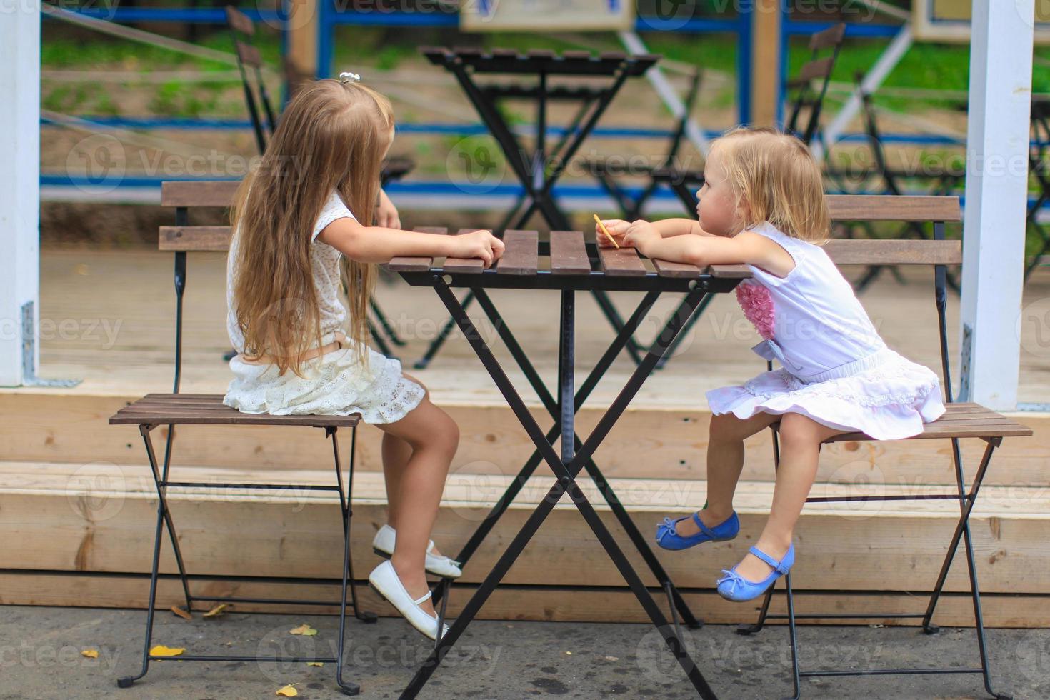 Little girls sitting on outdoors dining area photo