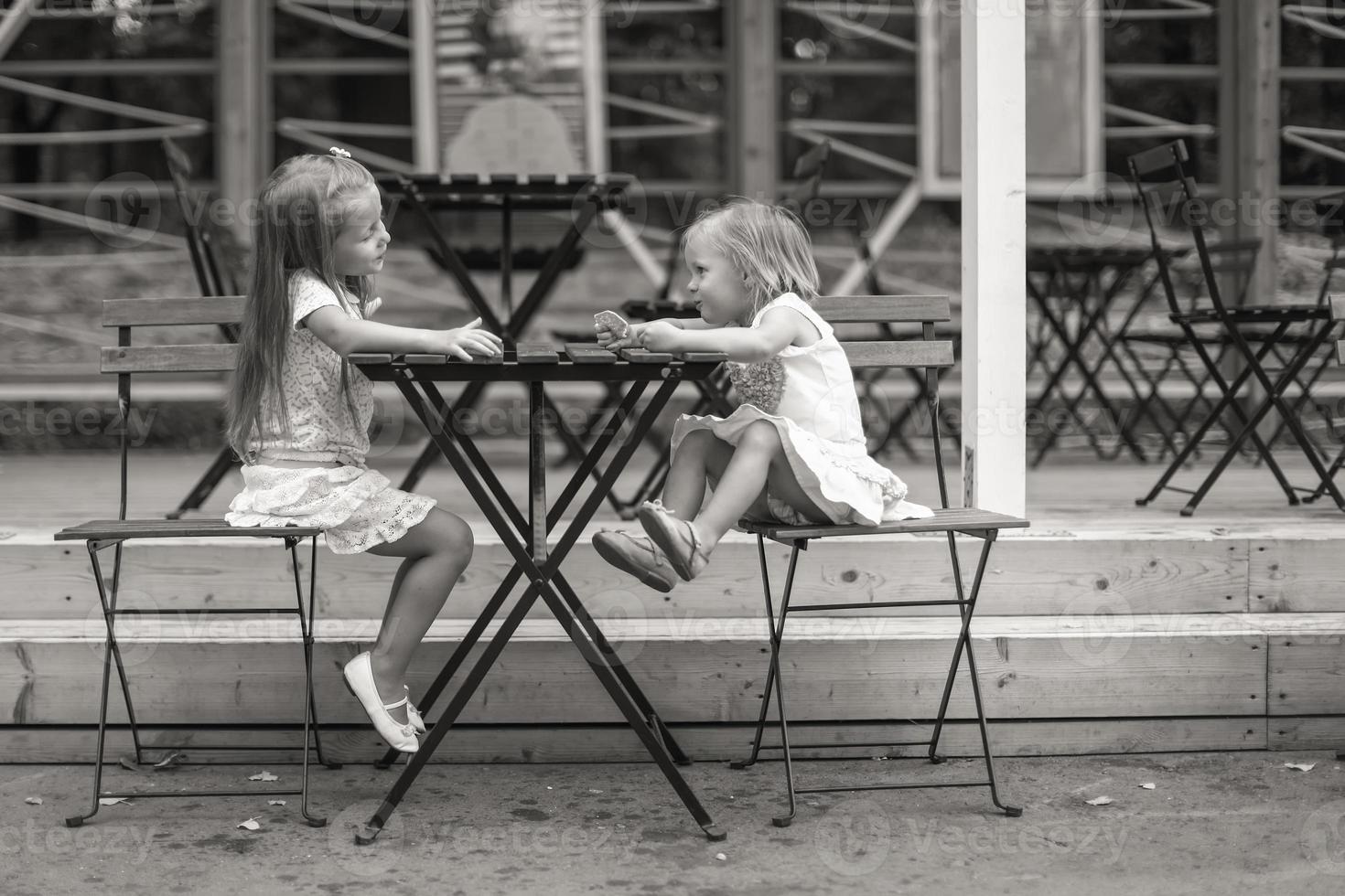 Little girls sitting on outdoors dining area photo