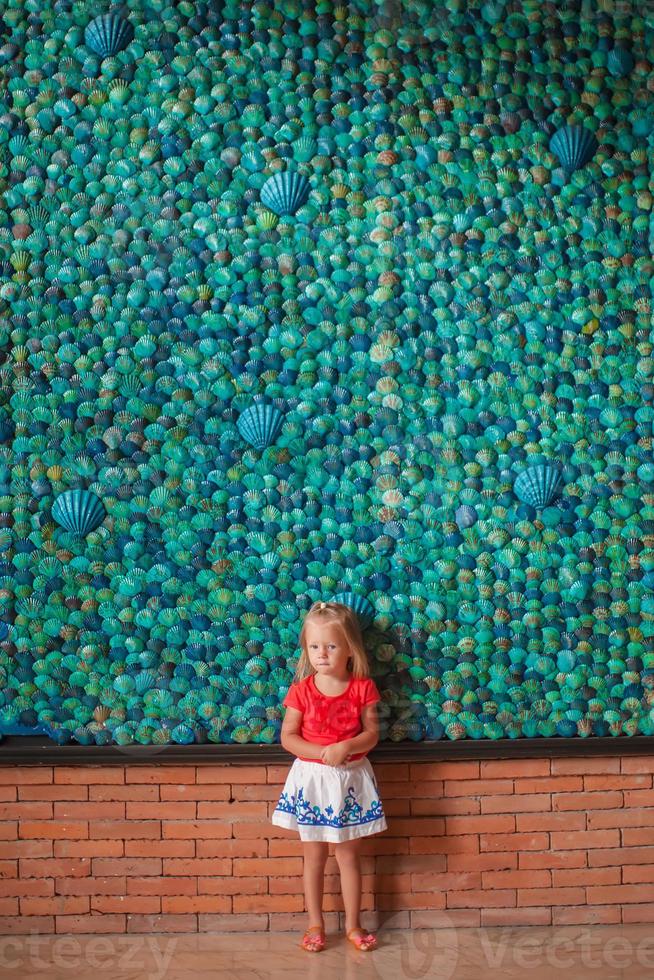 Little girl by a wall with blue shells photo