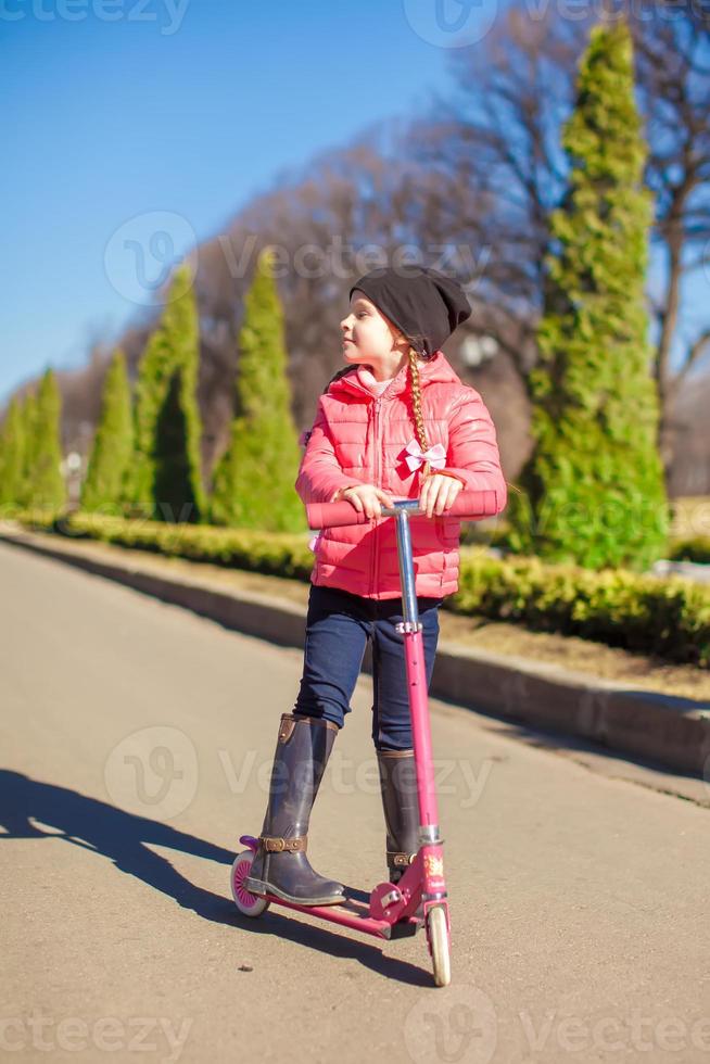 Little girl riding a scooter outdoors photo