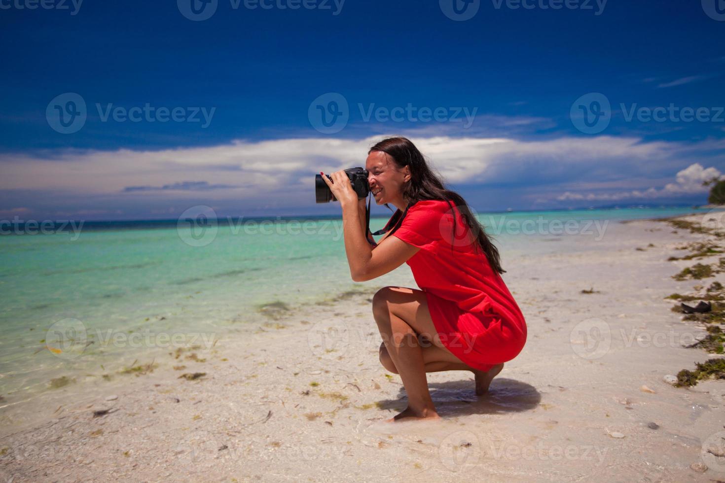 Beautiful brunette woman on the beach taking photos