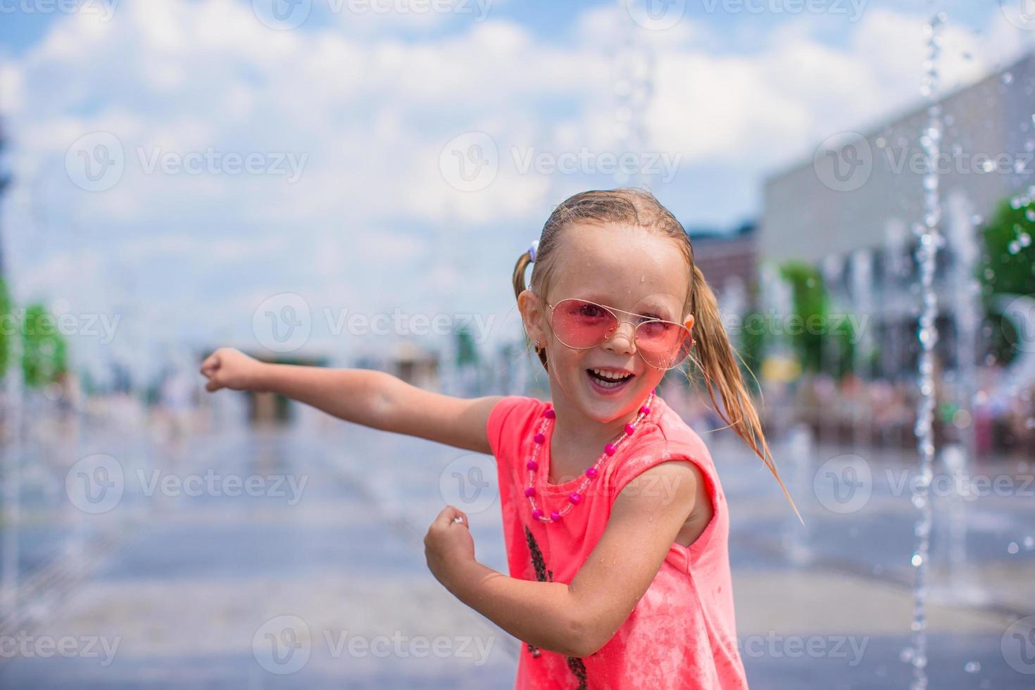 Little girl playing on a water fountain photo