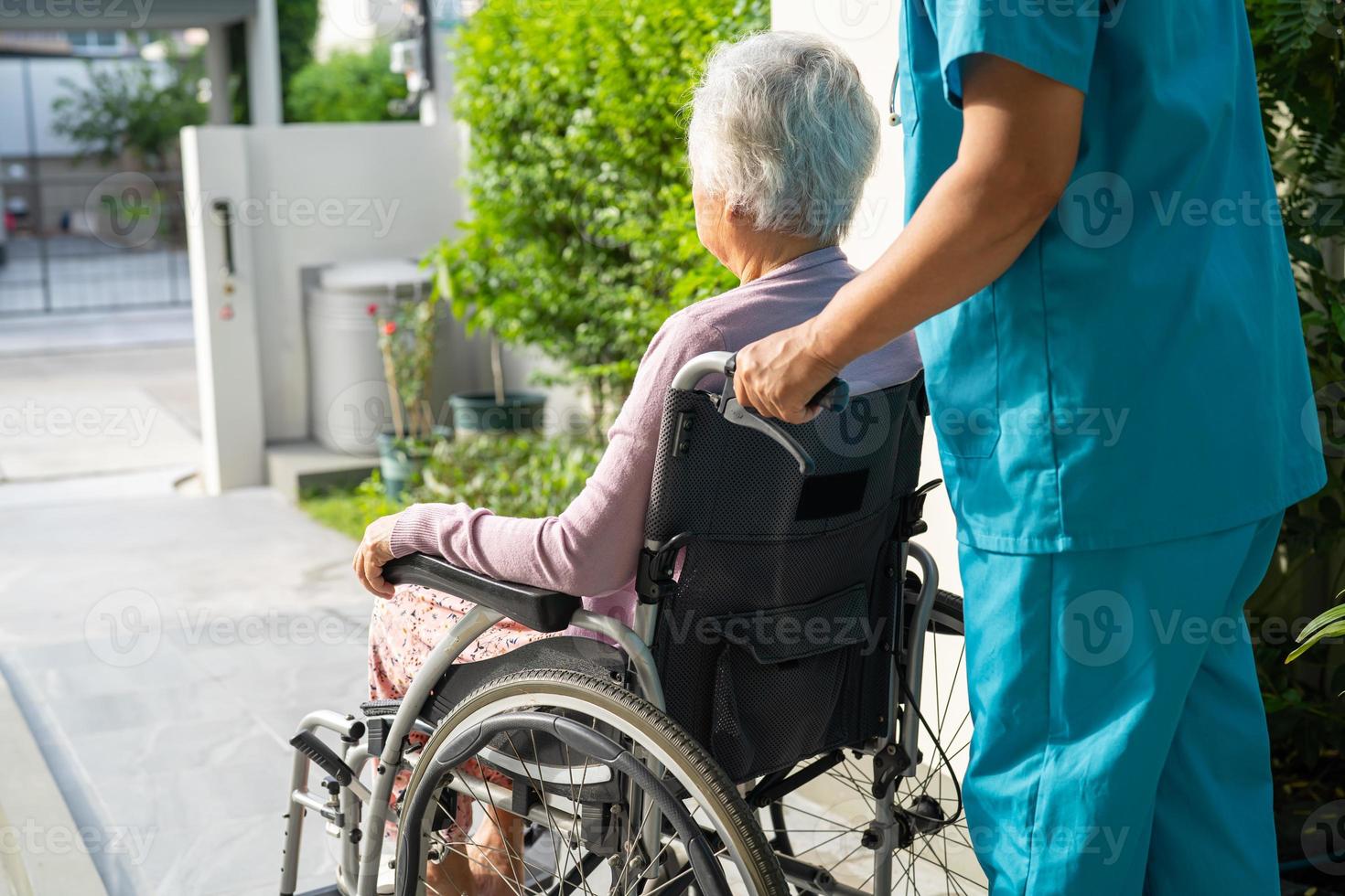 Caregiver help and care Asian senior or elderly old lady woman patient sitting on wheelchair to ramp in nursing hospital, healthy strong medical concept. photo