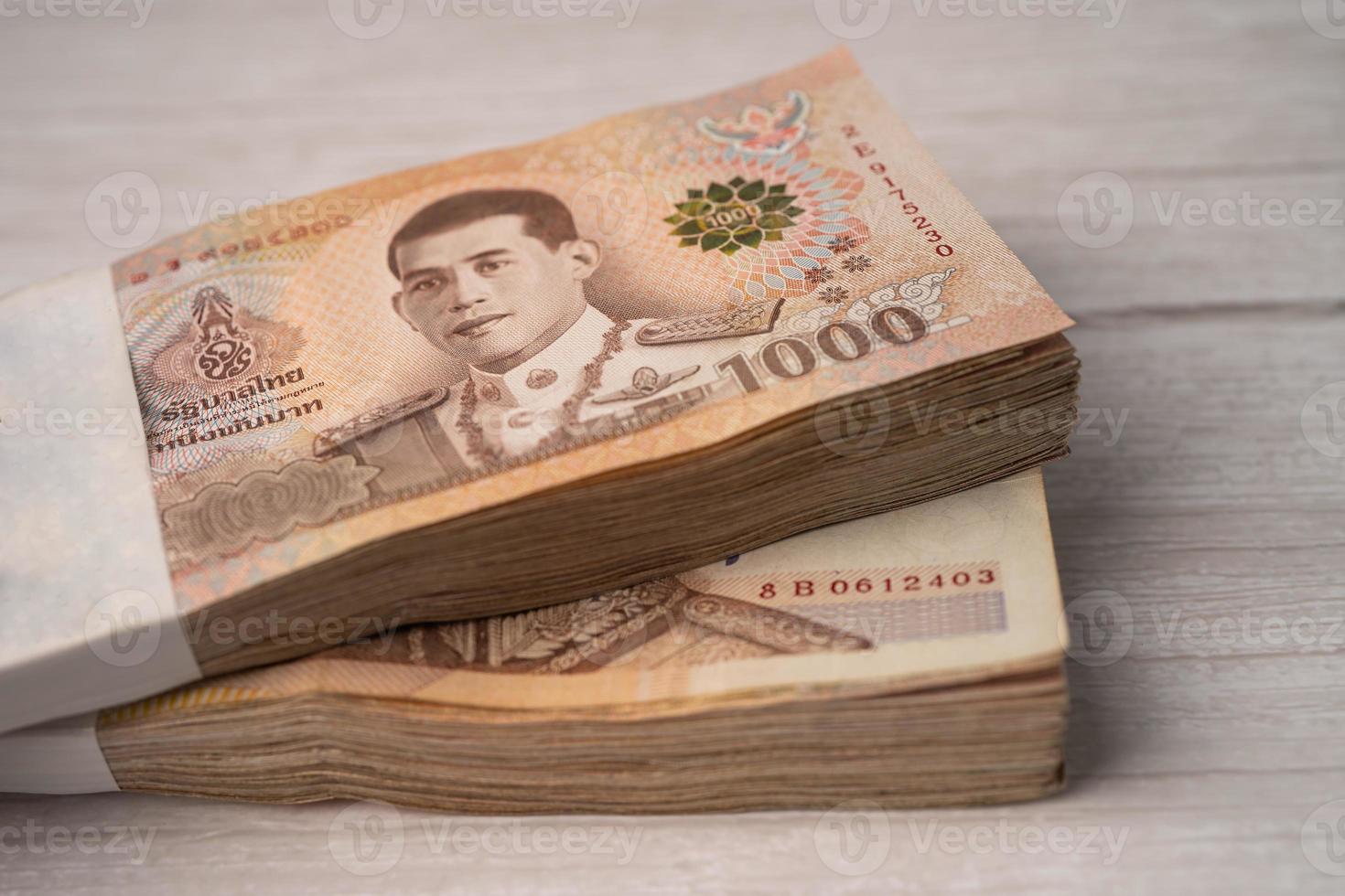 Stack of Thai baht banknotes on wooden background, business saving finance investment concept. photo