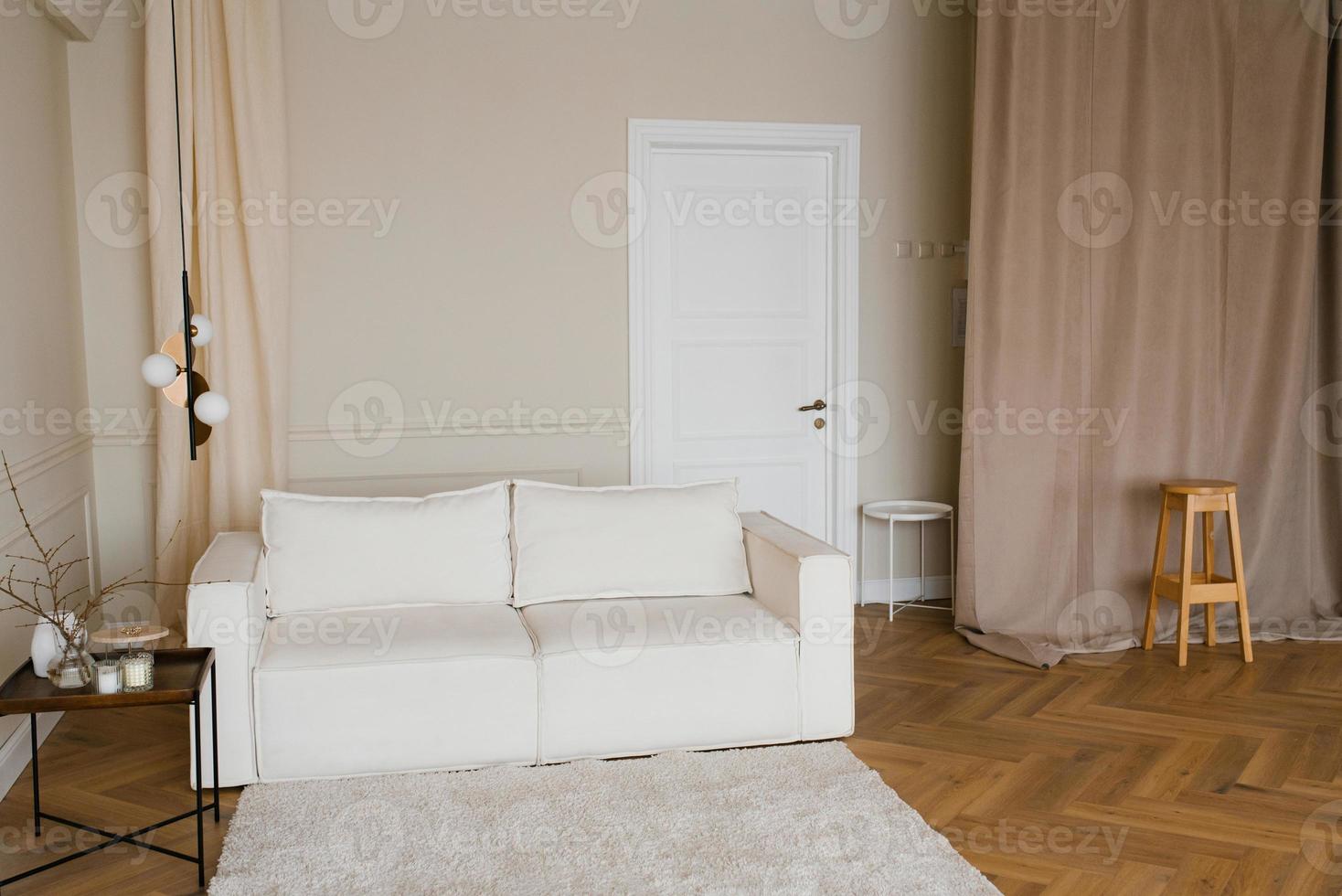 Scandinavian interior with a light sofa on a wooden parquet floor, a wooden side table and beige walls photo