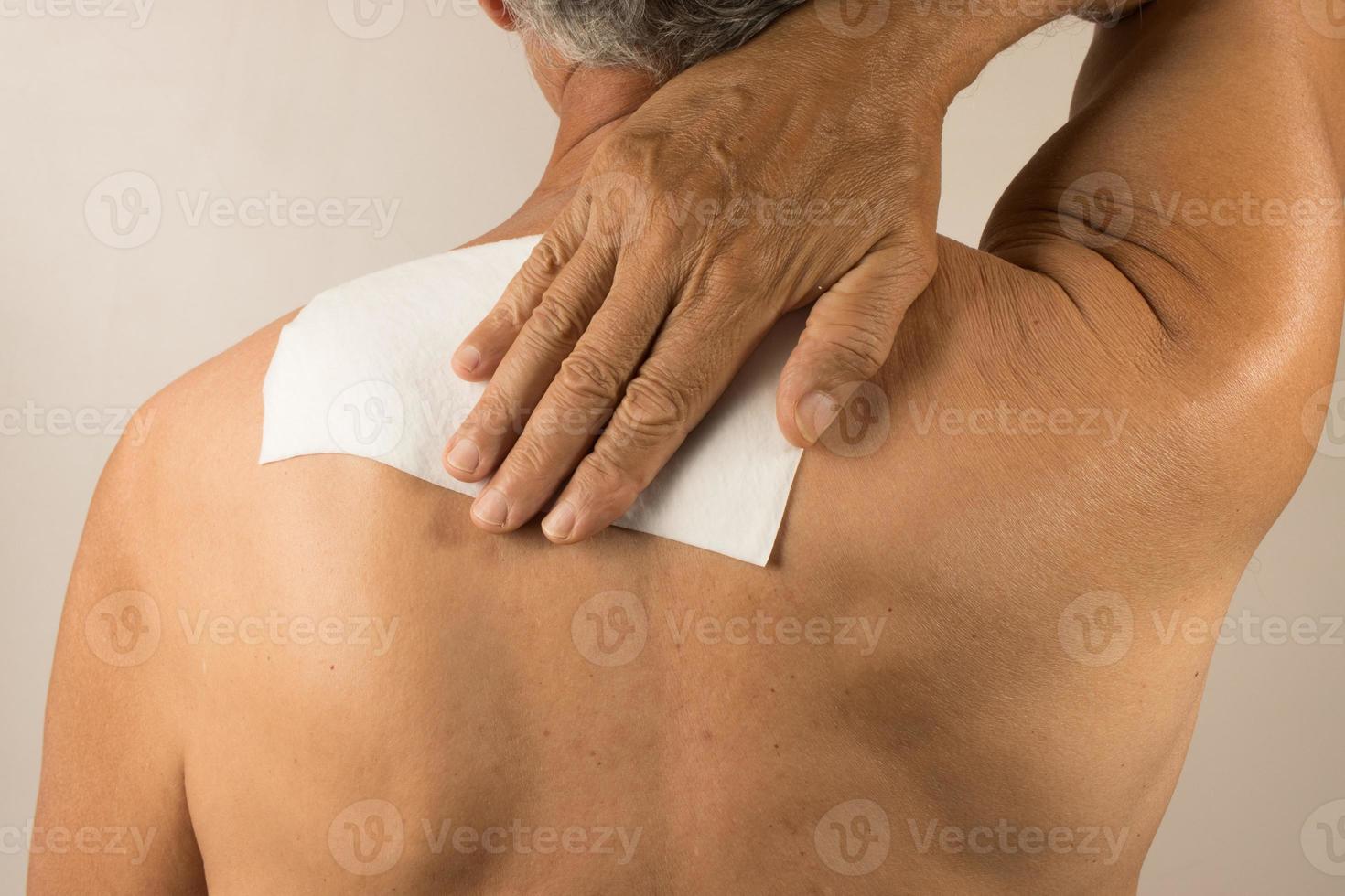 hombre vistiendo un medicado parche para dolor alivio cerca su hombro espada y Superior atrás. foto