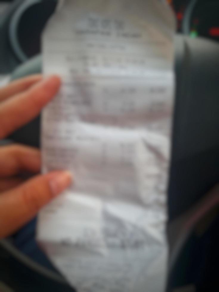 Defocused blurred photo of A hand is holding a shopping receipt