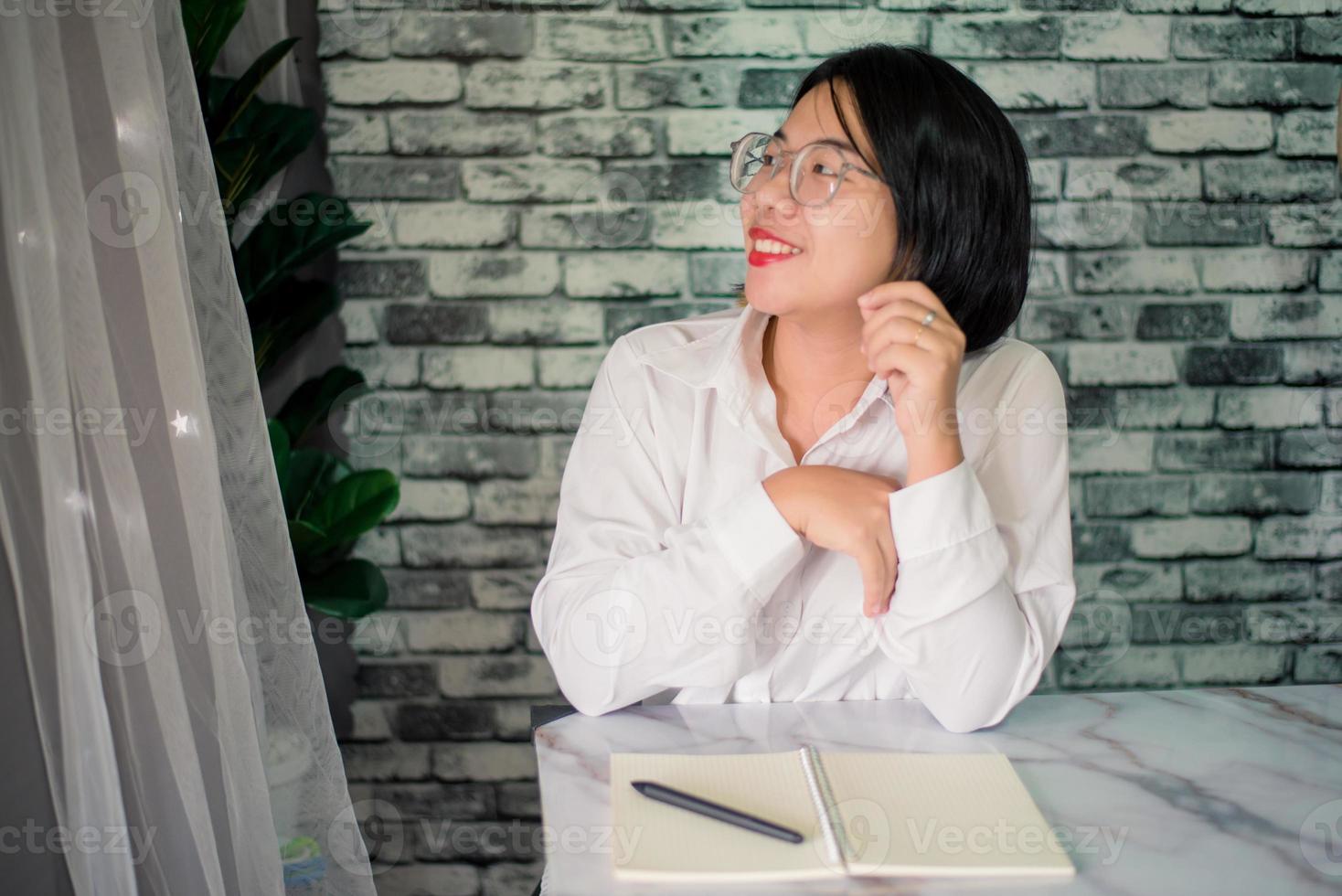 hermoso joven sonriente mujer de negocios trabajando a oficina con ordenador portátil en escritorio foto