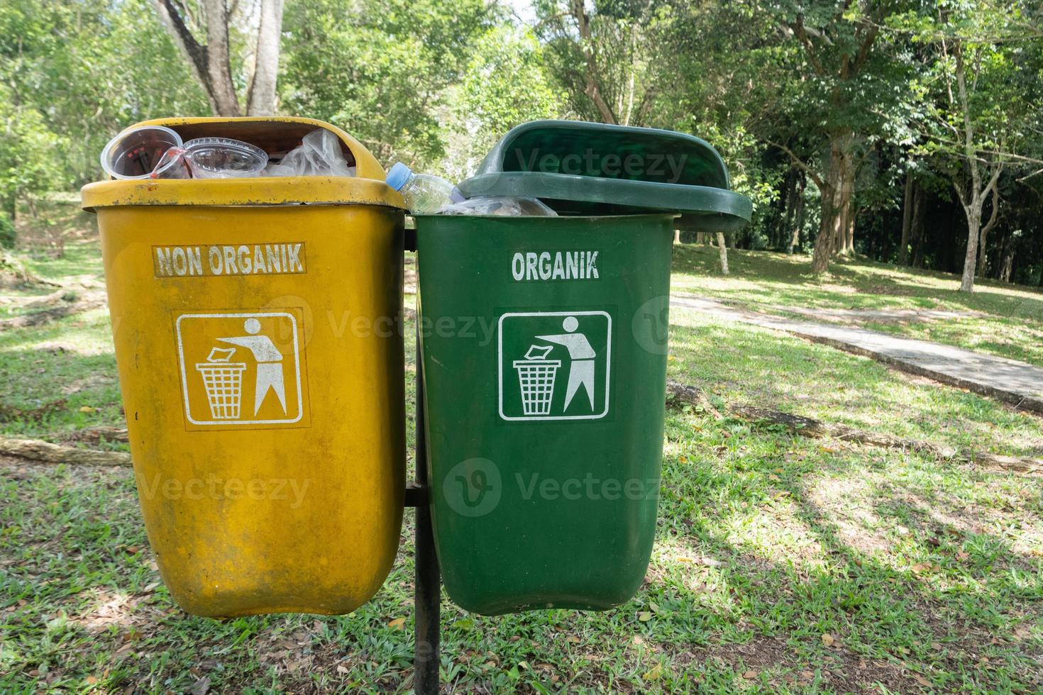 focus focus on the two yellow and green trash cans, green for recyclable waste, yellow non-recyclable trash in the recreation park area, soft focus photo